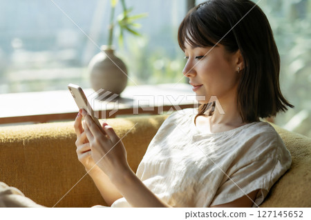 一位女士在客廳使用智慧型手機 生成式人工智慧 127145652