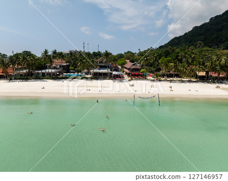 Resorts lined along the sandy beach with turquoise waters and lush tropical backdrop. Ko Pha Ngan, Thailand. 127146957