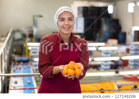 Cheerful girl sorting mandarins on conveyor line of factory 127148206