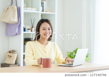 使用一台電腦在客廳裡的年輕女子 127148746