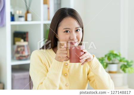 Young woman drinking coffee in the living room Young woman drinking coffee in the living room 127148817
