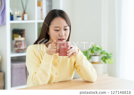 Young woman drinking coffee in the living room 127148818
