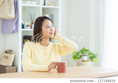Young woman drinking coffee in the living room Young woman drinking coffee in the living room 127148819