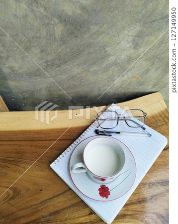 Notebook, pen, glasses and a cup of milk on the wooden table 127149950