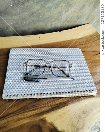 Notebook with pen and glasses on wooden table. professional workspace organization. Top view Notebook with pen and glasses on wooden table. professional workspace organization. Top view 127150189