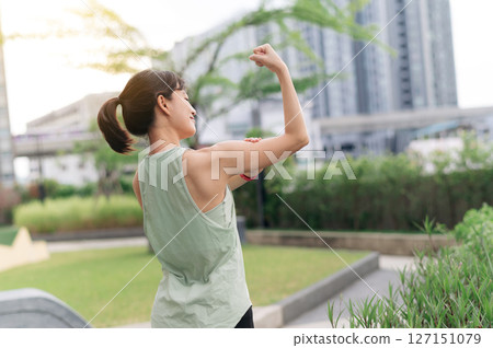 Focused asian woman in an urban city at sunset. fitness yoga workout with stretching exercise reduces shoulder pain muscle strain inflammation and injury risk for medical wellness and healthcare 127151079