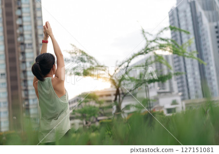 Asian woman enjoys sunset fitness yoga workout. stretching exercise reduces medical injury risk like shoulder pain inflammation or muscle strain promoting wellness and healthcare in an urban city 127151081