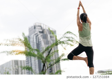 Focused asian woman in an urban city at sunset wellness fitness yoga workout with stretching exercise reduces medical shoulder pain muscle strain inflammation and lowers injury risk for healthcare 127151084
