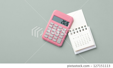 Pink calculator with 2026 and calendar on green background, new year financial resolutions, budget planning, top view 127151113