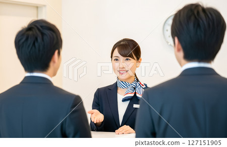 A female employee attending to visitors at the reception desk of a large company A female employee attending to visitors at the reception desk of a large company 127151905