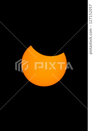 Bright orange sun shines against the darkness in a partial solar eclipse celestial event. 127152057