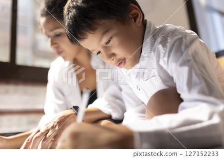 Focused asian boy drawing next to his mother at home 127152233