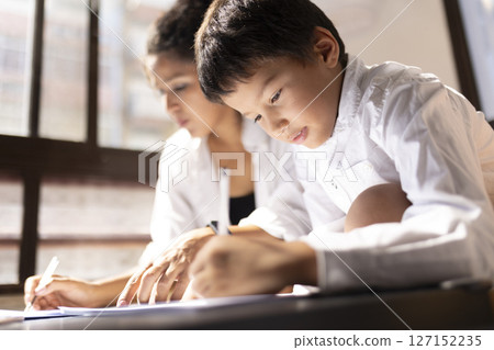 Young boy learning and studying with his tutor or mother 127152235