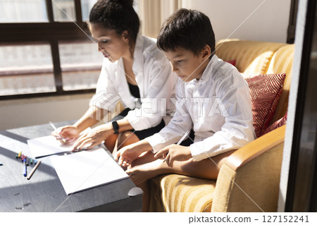 Focused mother and son drawing together at home Focused mother and son drawing together at home 127152241