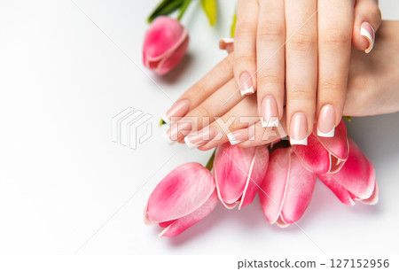 Woman showing french manicure and pink tulips on white background Woman showing french manicure and pink tulips on white background 127152956