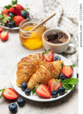 Delicious breakfast with croissants, coffee, berries and honey enjoying morning meal 127152960
