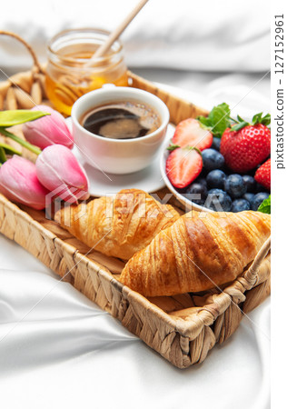 Romantic breakfast in bed with coffee, croissants, berries, honey and tulips 127152961