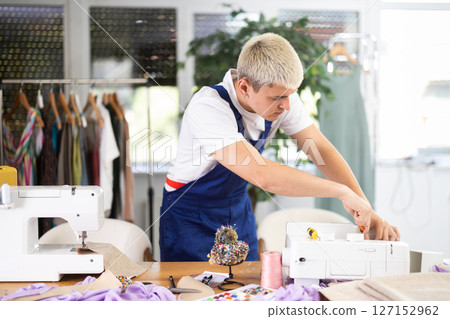 Repairman repairing sewing machine in workshop 127152962