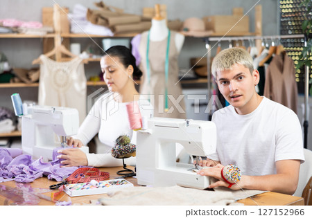 Two seamstresses male and female working on sewing machines in sewing workshop 127152966