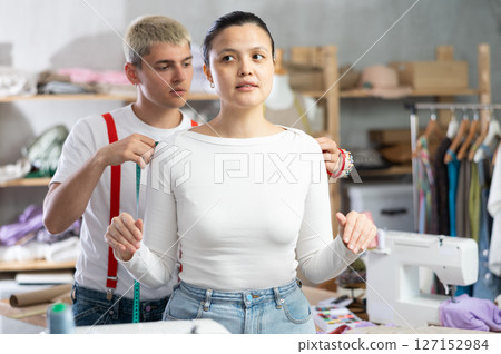 Male tailor taking measurements from Asian client Male tailor taking measurements from Asian client 127152984