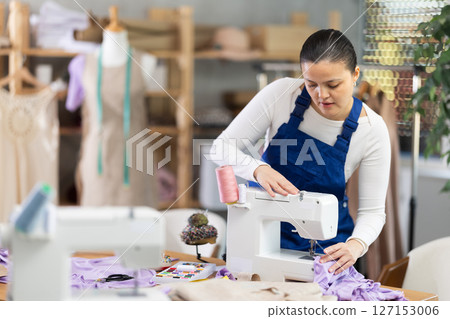 Female repairman fixing sewing machine 127153006