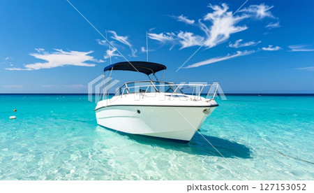 Turquoise water laps against a tropical beach, with a lone boat resting on the sand under a vast blue sky, inviting summer travel and island vacations 127153052