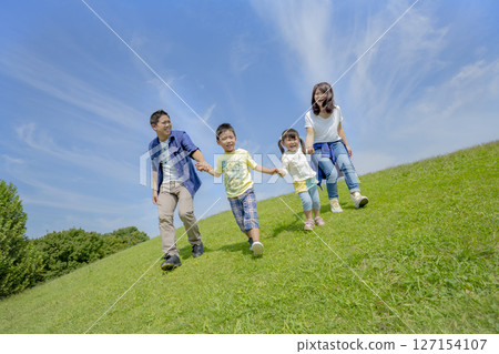 一家四口在公園的小山上玩耍 127154107