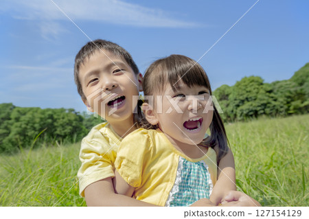 Brother and sister playing on the hill in the park 127154129