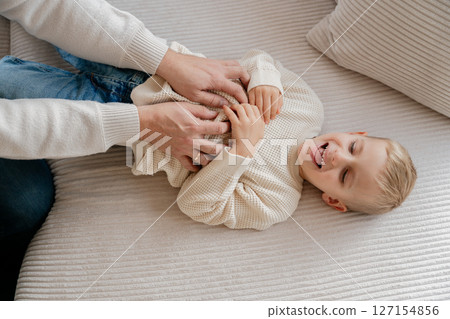 Close-up of a 4-year-old boy's face laughing from tickling his dad at home on the couch. High quality photo Close-up of a 4-year-old boy's face laughing from tickling his dad at home on the couch. High quality photo 127154856