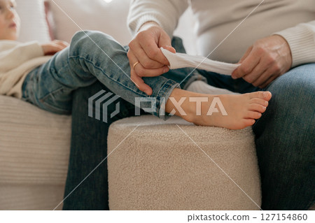 Dad slowly pulls down and pulls the white socks off the baby's feet. High quality photo Dad slowly pulls down and pulls the white socks off the baby's feet. High quality photo 127154860