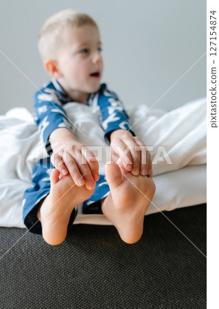 a little blond-haired boy in blue pajamas in his parents' bed lounging in the white sheets. High quality photo a little blond-haired boy in blue pajamas in his parents' bed lounging in the white sheets. High quality photo 127154874