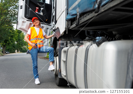 Portrait young adult happy smiling woman climbing cabin heavy truck driver cargo vehicle. Female person girl professional job career working driving freight engine lorry. Logistics industry Portrait young adult happy smiling woman climbing cabin heavy truck driver cargo vehicle. Female person girl professional job career working driving freight engine lorry. Logistics industry 127155101