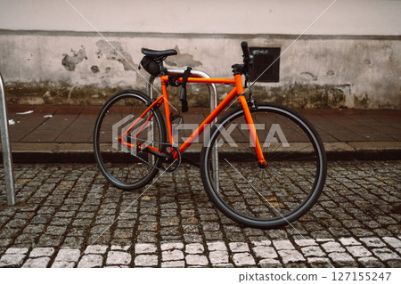 Orange Bicycle Parked on Cobblestone Street Orange Bicycle Parked on Cobblestone Street 127155247
