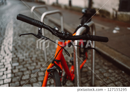 Handlebar View of an Orange Bicycle on Wet Cobblestones Handlebar View of an Orange Bicycle on Wet Cobblestones 127155295