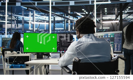 Data center worker with paraplegia using green screen PC to apply node tree programming. Server hub admin with disability uses visual programming on mockup computer to identify data patterns, camera A Data center worker with paraplegia using green screen PC to apply node tree programming. Server hub admin with disability uses visual programming on mockup computer to identify data patterns, camera A 127155594