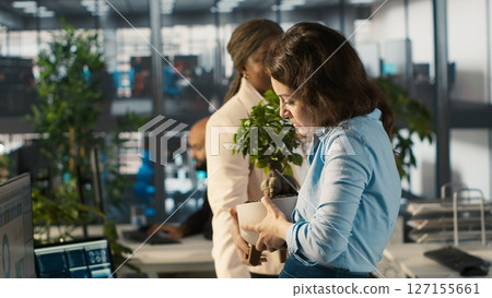 Employee getting consoled by colleagues after being fired, leaving office. Worker holding box filled with desk plants saying goodbye to coworkers after being laid off, camera A Employee getting consoled by colleagues after being fired, leaving office. Worker holding box filled with desk plants saying goodbye to coworkers after being laid off, camera A 127155661
