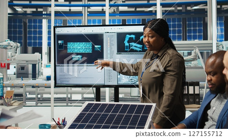 Shareholders discussing future investment opportunities in sustainable energy manufacturing. Management executives and investors in solar panels plant reviewing solar technology reports, camera A Shareholders discussing future investment opportunities in sustainable energy manufacturing. Management executives and investors in solar panels plant reviewing solar technology reports, camera A 127155712