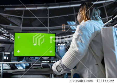 Female astronaut in spacecraft verifying navigation coordinates using green screen monitor. Woman in spaceship updating flight log on chroma key PC display during planetary exploration flight 127155966