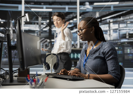Annoyed data center engineer leaving after having fight with coworker over performance issues. Irritated woman in server farm departing from colleague desk after finishing dispute 127155984
