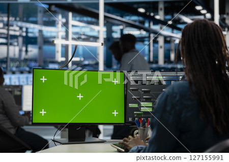 Engineer working on isolated screen desktop PC in data center housing storage infrastructure. IT professional using chroma key computer display in server hub workspace filled with networking tech 127155991