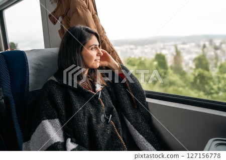 Young woman traveling by train and looking out the window . 127156778