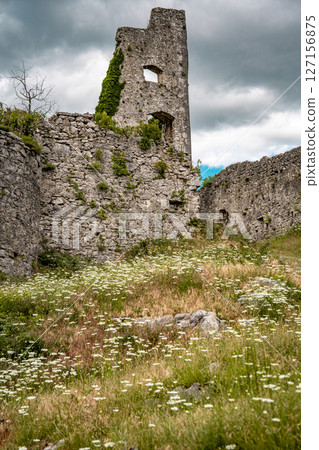 Ruins Of Grad Vipava In Slovenia: Ancient Stone Walls Covered In Ivy Standing On A Grassy Hilltop Under A Dramatic Cloud-Filled Sky In The Scenic Vipava Valley 127156875