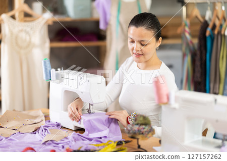 Asian woman sewing on a sewing machine in a workshop Asian woman sewing on a sewing machine in a workshop 127157262