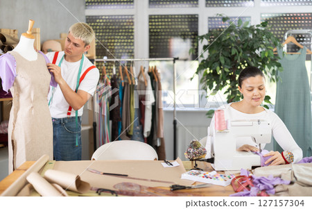 Asian woman sewing clothes on the background of a guy with a mannequin 127157304