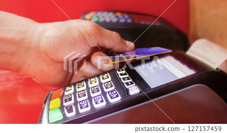 A man pays in a store with a bank card through a contactless terminal 127157459