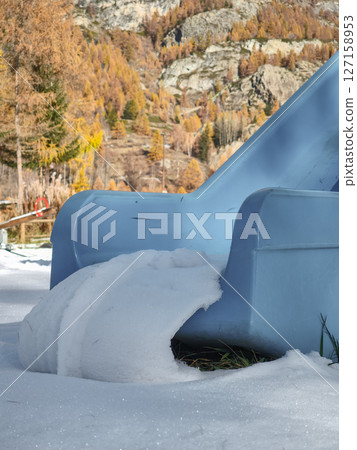 Snow dusted blue slide nestled among autumnal trees, rocky mountains framing scenic aosta landscape in late autumn Frazionne Lillaz 127158953