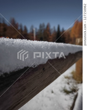 Close up of a wooden fence dusted with fresh snow, set against a backdrop of autumn trees in aosta, italy during november Frazionne Lillaz Close up of a wooden fence dusted with fresh snow, set against a backdrop of autumn trees in aosta, italy during november Frazionne Lillaz 127158962