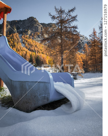 Snow dusted blue playground slide nestled among autumn trees, mountain landscape of aosta valley, italy, winter approaching Frazionne Lillaz 127158979