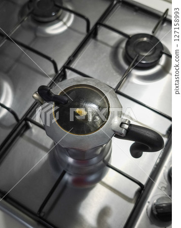 Moka pot brewing aromatic coffee on stainless steel gas stove traditional italian coffee preparation method in aosta Moka pot brewing aromatic coffee on stainless steel gas stove traditional italian coffee preparation method in aosta 127158993