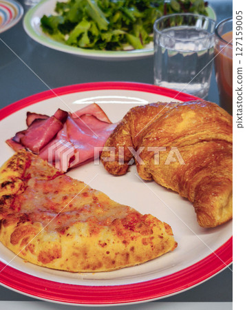 Breakfast pizza slice, croissant, ham, greens and beverages water and juice Breakfast pizza slice, croissant, ham, greens and beverages water and juice 127159005